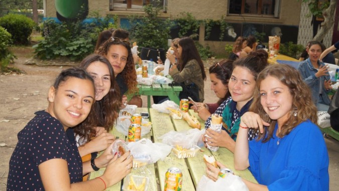 Eine Gruppe junger Frauen des Lycée Notre Dame de Bon Secours sitzt lachend im Gartenbereich der Schule zusammen.