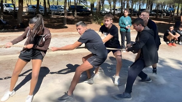 Eine Gruppe von Schülerinnen und Schülern versammelt sich im Außenbereich mit Bäumen auf dem Gelände des Lycée Notre Dame de Bon Secours.