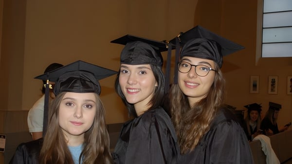 Drei Schülerinnen in Abschlusskleidung posieren zusammen auf dem Campus des Lycée Polyvalent Philippine Duschenes.