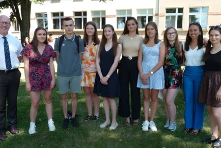 Eine Gruppe von Schülerinnen und einem Schüler steht gemeinsam draußen vor dem Gebäude des Lycée Saint Antoine.