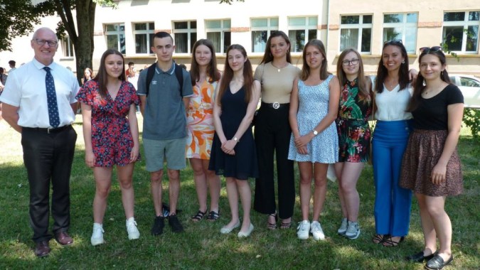 Eine Gruppe Schülerinnen und Schüler steht vor einem großen Fenster des Schulgebäudes des Lycée Saint Antoine.