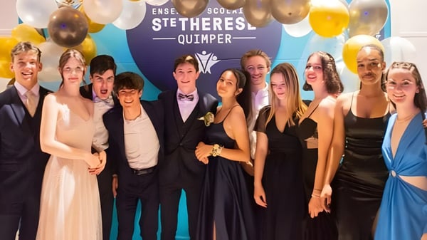 Eine Gruppe formell gekleideter Schülerinnen und Schüler posiert vor einem Hintergrund mit dem Schriftzug Lycée Sainte Thérèse Quimper.