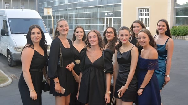 Eine Gruppe junger Frauen steht vor einem Gebäude mit großen Glasfenstern auf dem Campus des Lycée Sainte Thérèse.