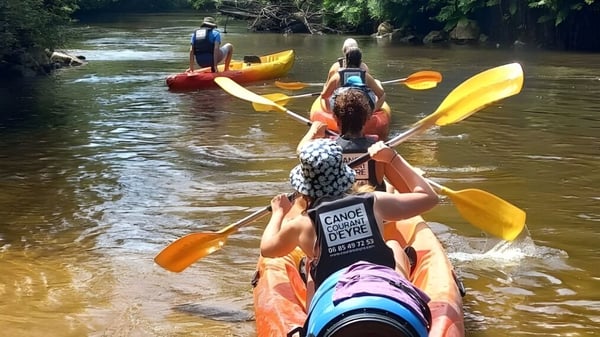 Schüler des Lycée St Elme paddeln in bunten Kajaks auf einem Fluss mit grüner Ufervegetation.
