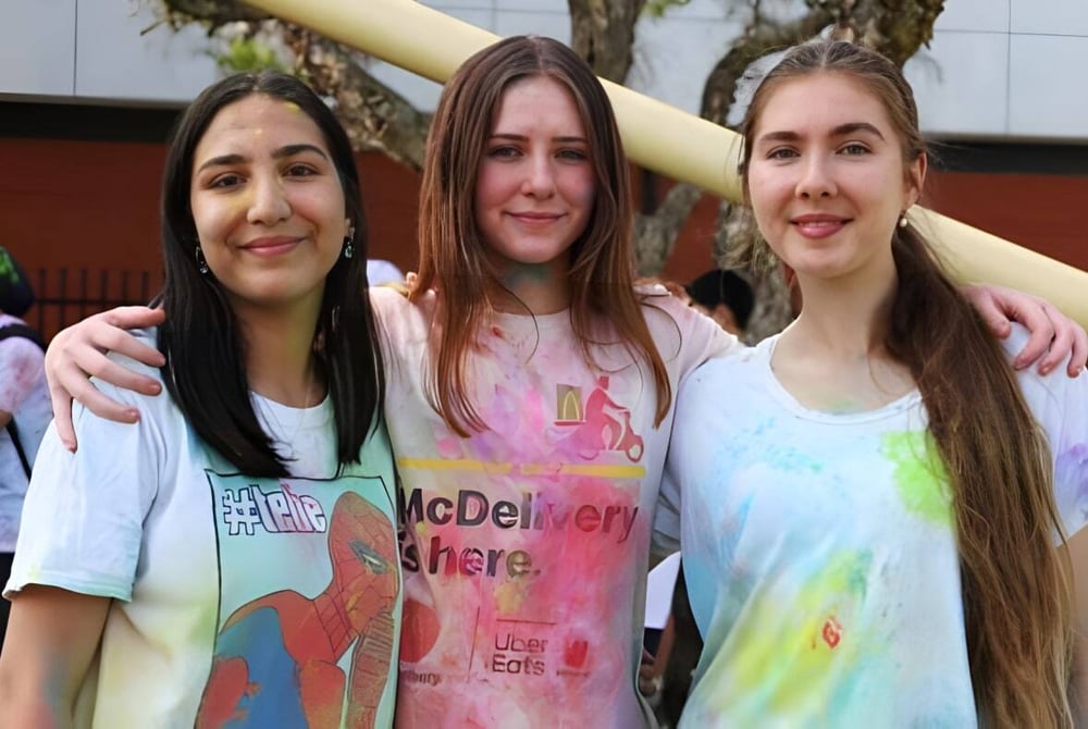 Drei Schülerinnen stehen umarmt zusammen auf dem Außengelände der Lynwood Senior High School.