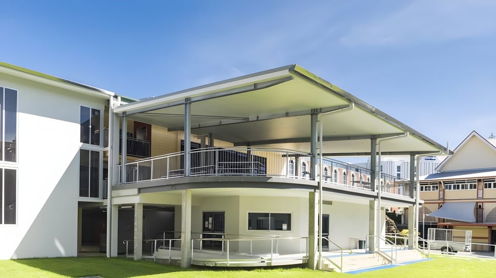 Ein modernes Wohngebäude mit Balkon und Rasenfläche vor dem klaren Himmel auf dem Gelände der Mabel Park State High School.
