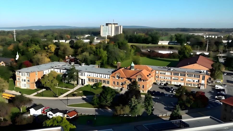 Luftaufnahme des Campus der Macdonald High School mit modernen und historischen Gebäuden inmitten grüner Hügel.
