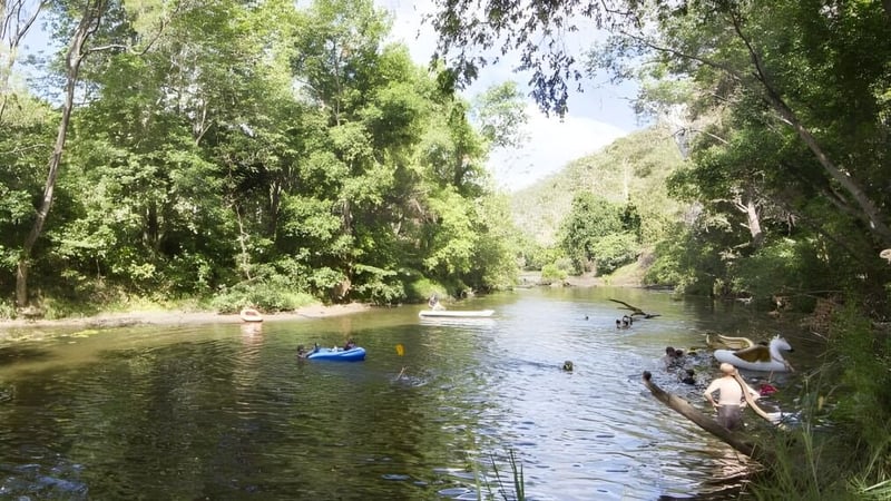 Schüler der MacGregor State High School genießen Wassersportaktivitäten wie Schwimmen und Bootfahren in einer ruhigen Flusslandschaft.
