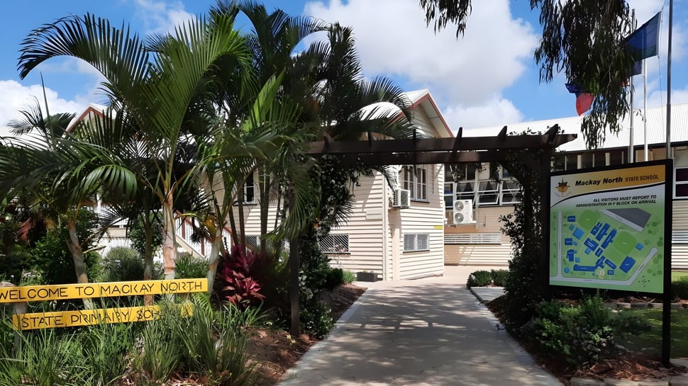 Das Gebäude der Mackay North State High School ist von tropischer Vegetation mit Palmen umgeben.