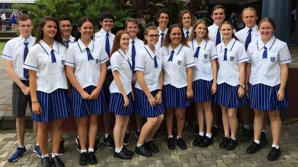 Eine Gruppe Schüler der Mackay North State High School steht zusammen im Freien auf einem gepflasterten Weg, umgeben von viel Grün.