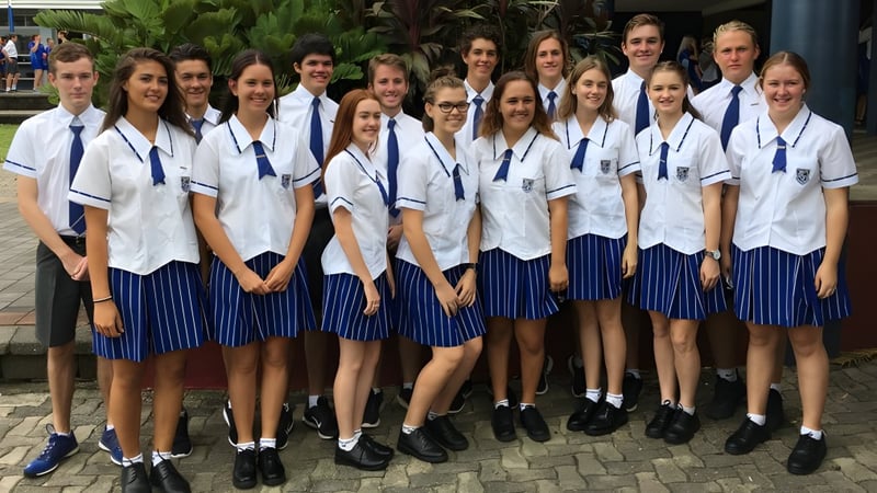Eine Gruppe Schüler der Mackay North State High School steht zusammen im Freien auf einem gepflasterten Weg, umgeben von viel Grün.