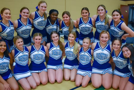 Eine Gruppe junger Cheerleaderinnen in blauen und weißen Uniformen posiert gemeinsam in einem Raum auf dem Campus der Mackay North State High School.