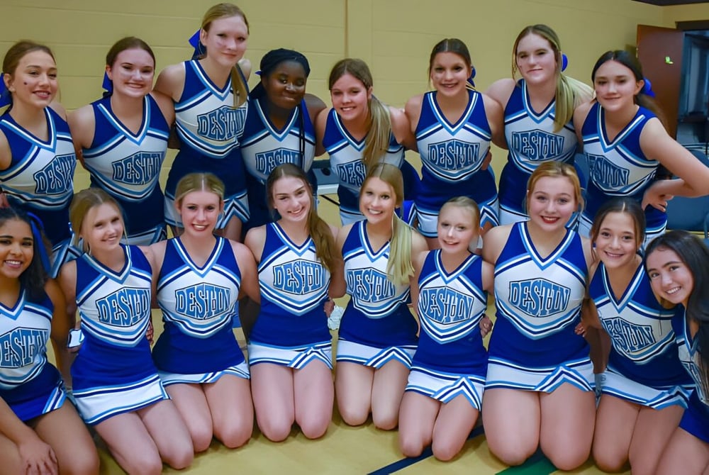 Eine Gruppe junger Cheerleaderinnen in blauen und weißen Uniformen posiert gemeinsam in einem Raum auf dem Campus der Mackay North State High School.