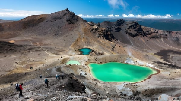 Im Vordergrund sind smaragdgrüne Teiche vor einer felsigen Landschaft zu sehen, im Hintergrund erheben sich schneebedeckte Berge auf dem Campus von Macleans College.