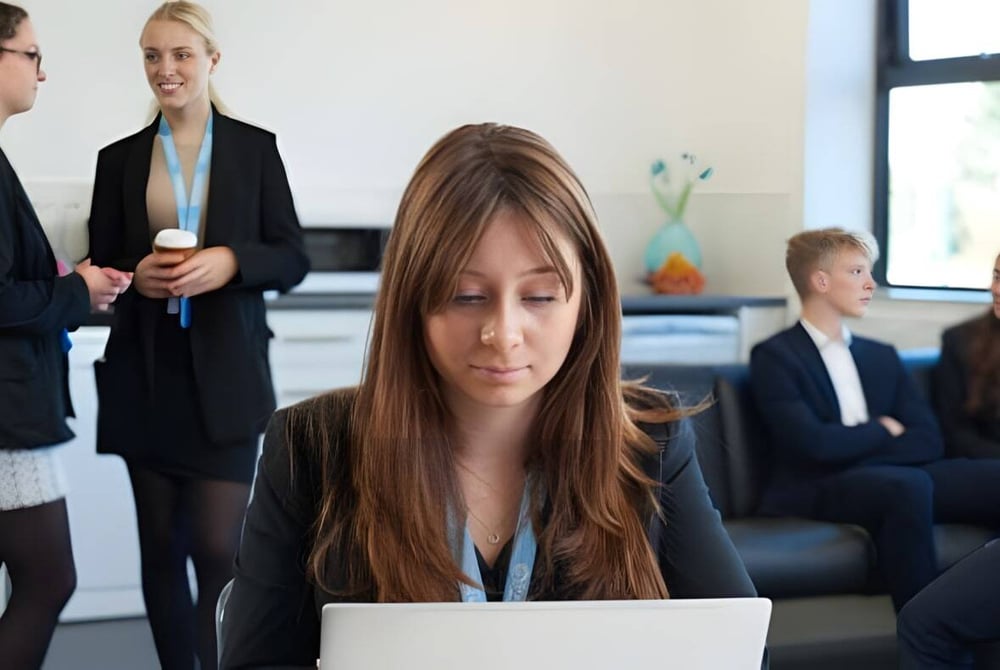 Eine junge Frau arbeitet an einem Laptop in einem Büro auf dem Campus der Magna Academy.
