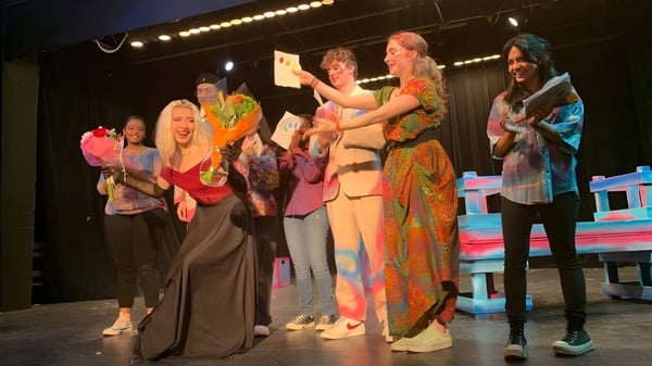 Schüler der Maharishi School stehen in bunten Kostümen auf der Bühne während eines Auftritts.