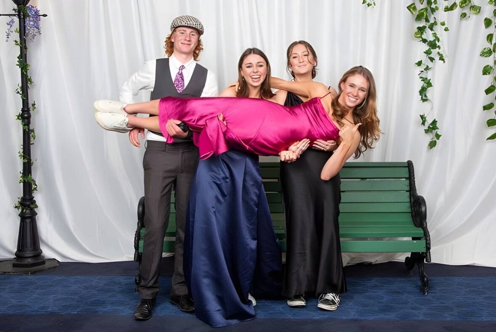 Eine Gruppe von vier Personen in formeller Kleidung steht vor einem grünen Hintergrund auf dem Gelände des Mahurangi College.