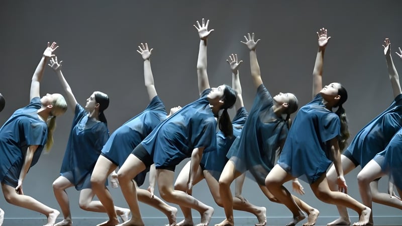 Schüler des Mahurangi College führen auf einer dunklen Bühne eine synchronisierte Tanzaufführung in blauen Kostümen auf.