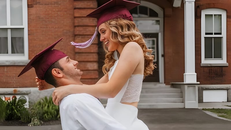 Ein junges Paar in Abschlussrobe umarmt sich vor einem Backsteingebäude auf dem Campus des Maine Central Institute.