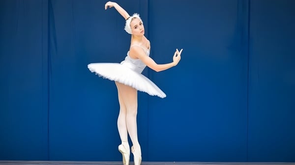 Eine Ballerina führt im Tanzunterricht am Maine Central Institute eine Pirouette vor blauem Hintergrund aus.