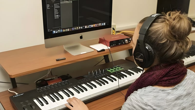 Eine Person mit Kopfhörern sitzt an einem Schreibtisch im Musikstudio des Maine Central Institute.