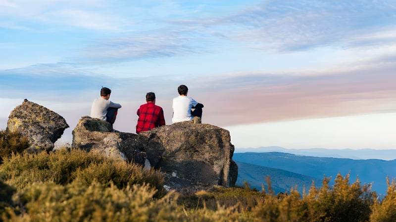 Drei Personen stehen auf einem Felsen und blicken auf die Berglandschaft beim Malanda State High School.