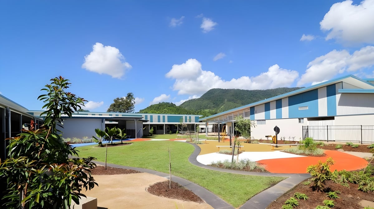 Das moderne und farbenfrohe Schulgebäude der Malanda State High School mit gepflegtem Außenbereich und Berglandschaft im Hintergrund.
