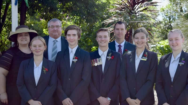 Absolventen der Maleny State High School stehen im grünen Außenbereich mit Palmen im Hintergrund.