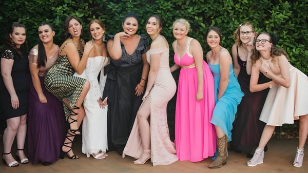 Eine Gruppe Schülerinnen der Maleny State High School posiert vor grünem Laub in verschiedenen festlichen Kleidern.