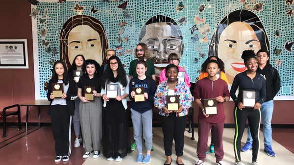 Eine Gruppe von Schülerinnen und Schülern steht vor einem bunten Wandbild auf dem Schulgelände der Mallard Creek High School.