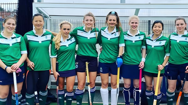 Eine Gruppe von Athletinnen steht vor dem eingezäunten Sportplatz auf dem Campus des Malvern College.