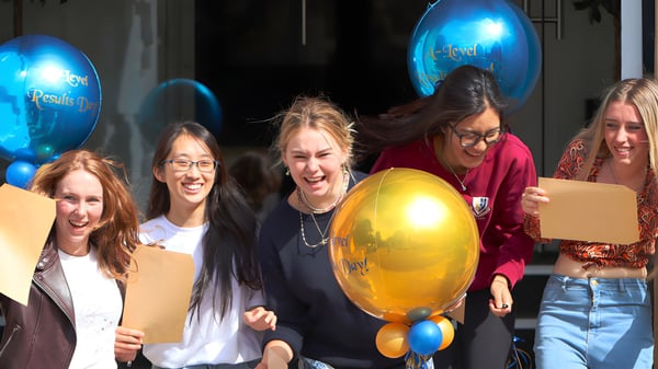 Eine Gruppe Schülerinnen der Malvern St. James Girls' School feiert mit bunten Ballons bei einer Indoor-Veranstaltung.