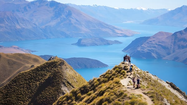 Zwei Schülerinnen und Schüler des Manawatu College stehen bei einer Wanderung auf einem Felsvorsprung mit Blick auf ein türkisfarbenes Bergsee.