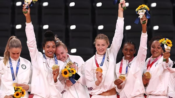 Weibliche Athletinnen der Mannahouse Christian Academy feiern mit Goldmedaillen und Sonnenblumen vor dunklem Hintergrund.