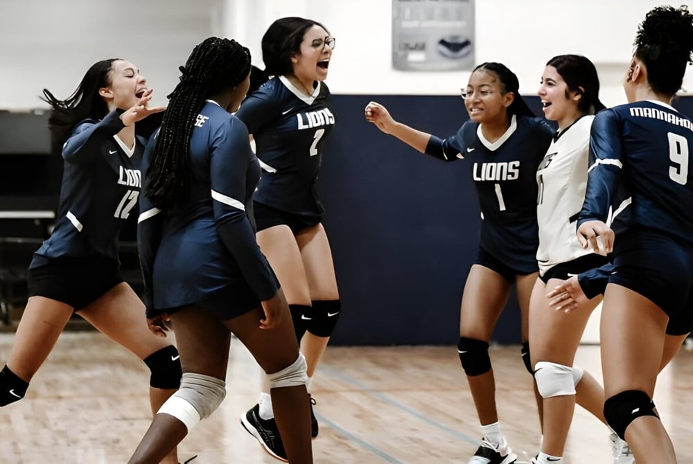 Weibliche Volleyballspielerinnen der Mannahouse Christian Academy feiern gemeinsam auf dem Spielfeld.