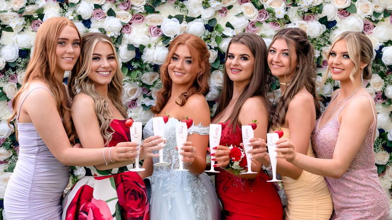 Eine Gruppe junger Schülerinnen der Manor House School feiert gemeinsam vor einem Blumenhintergrund mit Sektgläsern.