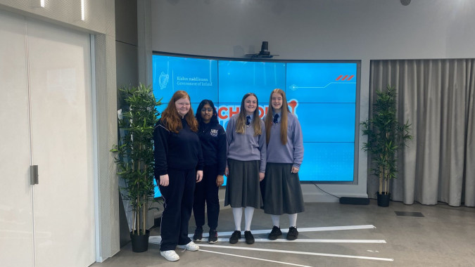 Eine Gruppe junger Schülerinnen steht in einem modernen Büro mit großen blauen Bildschirmen im Hintergrund auf dem Campus der Manor House School.