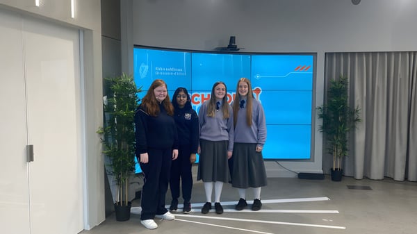 Eine Gruppe junger Schülerinnen der Manor House School steht in legerer Kleidung vor einem großen blauen Bildschirm in einem Innenraum mit Pflanzen.