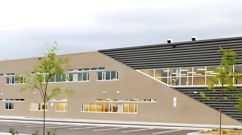 Das moderne mehrstöckige Gebäude der Maple Ridge Secondary School in Ontario ist von Bäumen und einem Parkplatz umgeben.