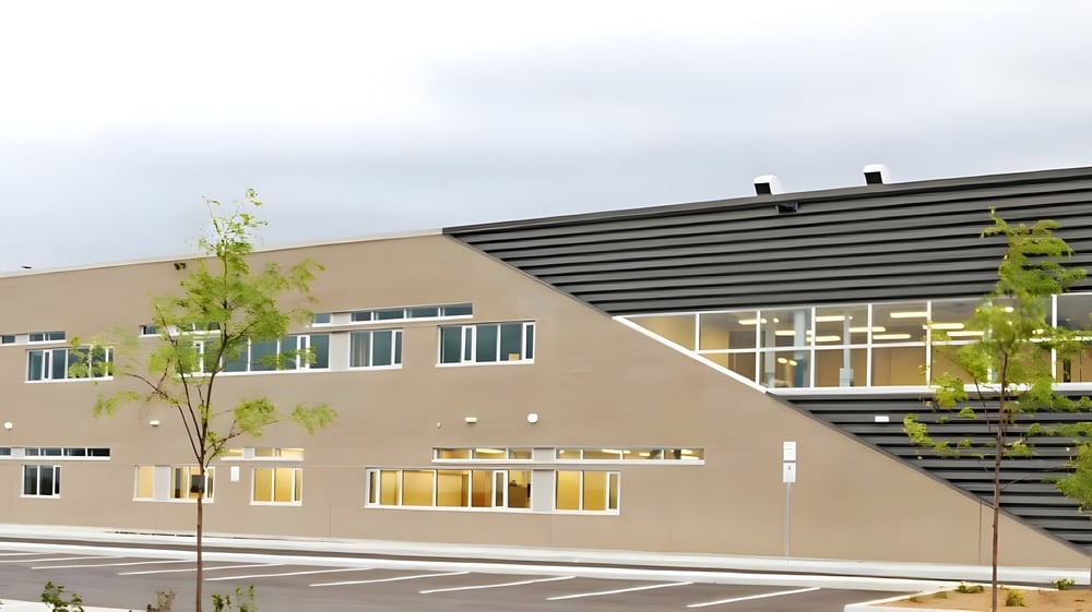 Das moderne mehrstöckige Gebäude der Maple Ridge Secondary School in Ontario ist von Bäumen und einem Parkplatz umgeben.