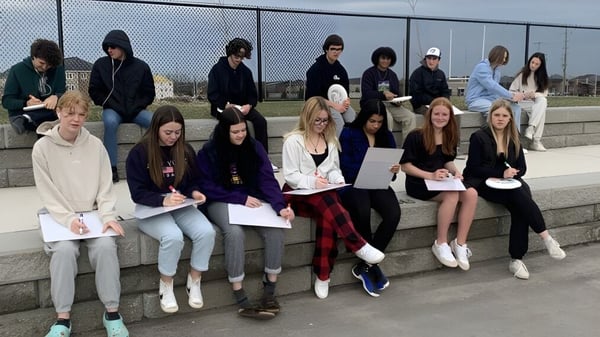 Eine Gruppe von Schülerinnen und Schülern sitzt auf einer Betonmauer im Außenbereich der Maple Ridge Secondary School in Ontario.