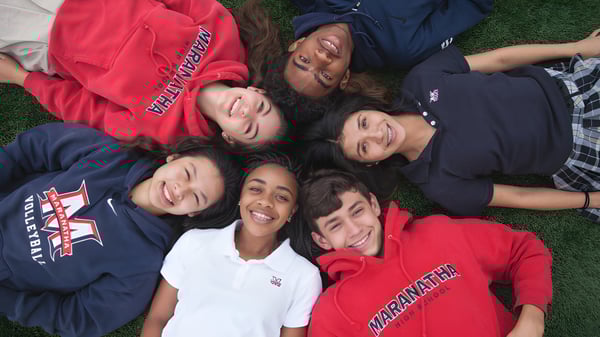Eine Gruppe von Schülern der Maranatha High School liegt in einem Kreis auf der Wiese und unterhält sich.