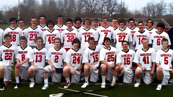 Eine Gruppe Schüler der Marblehead High School steht in weißen und roten Sportuniformen auf einem Rasenfeld mit Bäumen im Hintergrund.