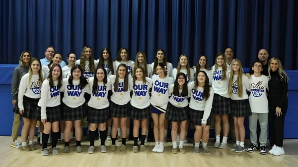 Eine Gruppe Schülerinnen steht in einheitlichen Uniformen vor einem blauen Vorhang auf dem Campus der Marian Catholic High School.