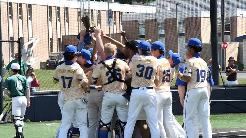 Eine Gruppe von Baseball-Schülern in Uniform steht auf dem Spielfeld vor dem Gebäude der Marian Catholic High School.