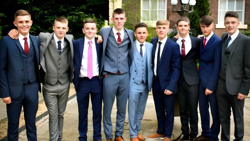 Eine Gruppe von jungen Männern in formeller Kleidung steht vor einem Gebäude auf dem Campus des Marian College.