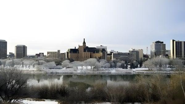 Ein zugefrorener See vor dem verschneiten Stadtbild mit hohen Gebäuden und einem schlossartigen Bauwerk im Hintergrund nahe Marion M. Graham Collegiate.