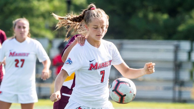 Eine junge Fußballspielerin mit weißem Trikot und der Nummer 7 dribbelt den Ball auf dem Spielfeld des Marist College.
