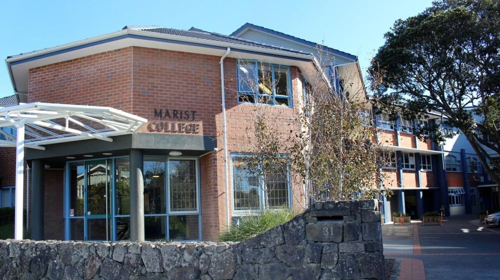 Das Backsteingebäude des Marist College ist von Bäumen und einer Steinmauer umgeben.