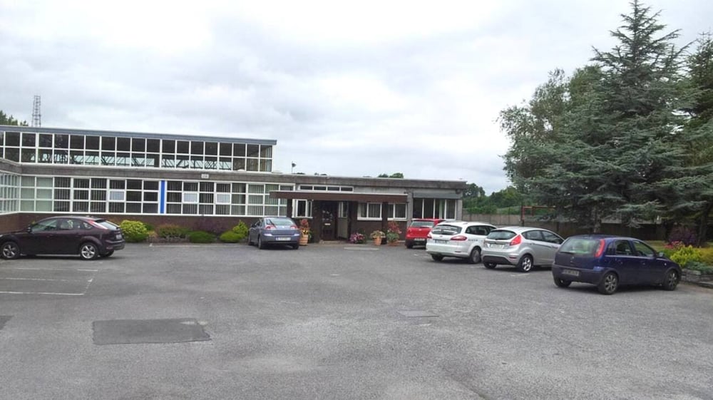Parkplatz mit mehreren Autos vor dem mehrstöckigen Gebäude auf dem Campus des Marist College bei bewölktem Himmel.